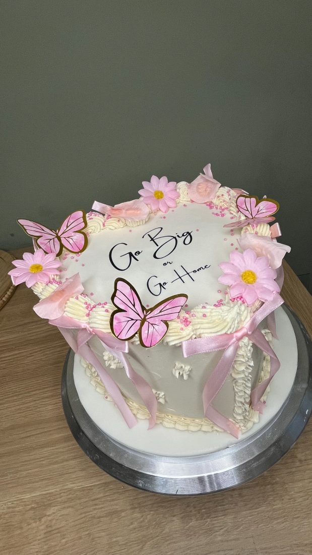 White vintage piped cake with pink butterflies and ribbon