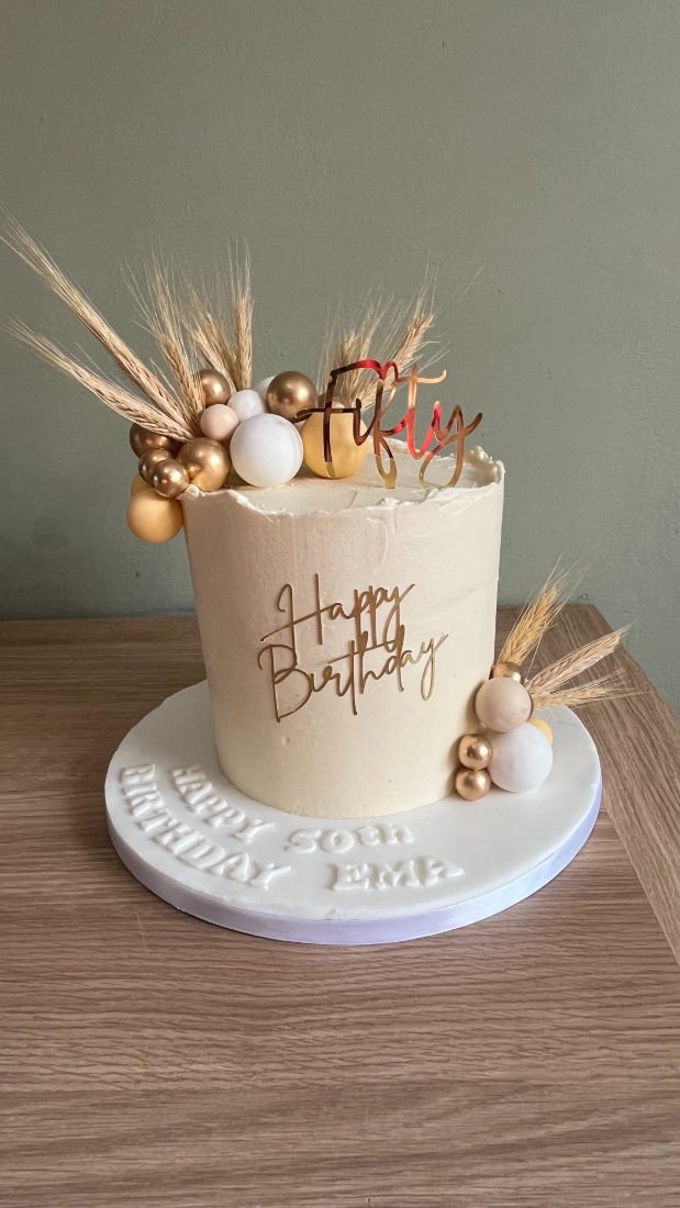 Cream fiftieth birthday cake with wheat and gold balls