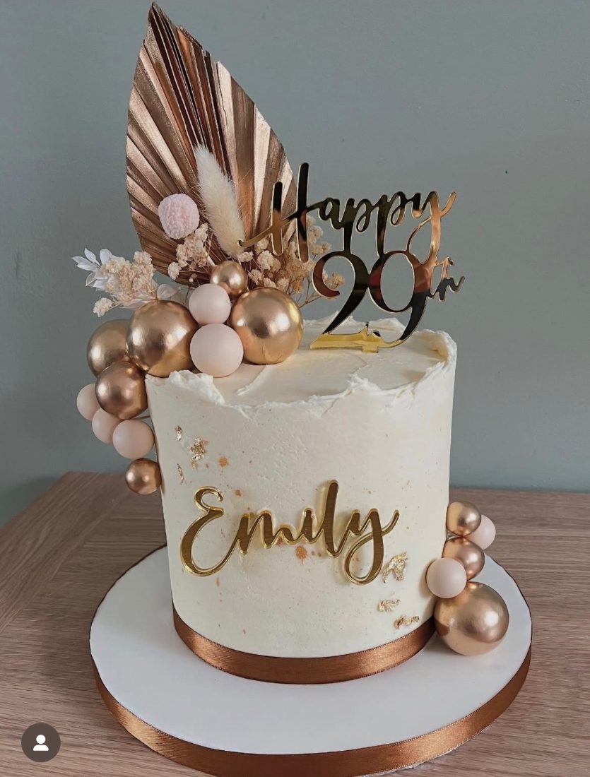 Ivory buttercream cake with gold spheres and dried palm