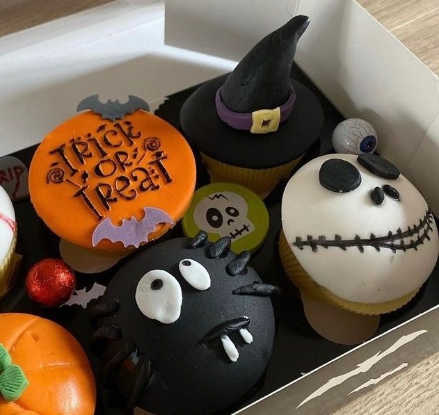Box of Halloween cupcakes with a witch hat, spider and skeleton faces