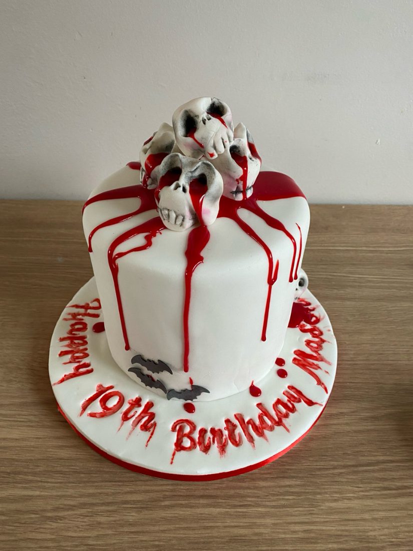 White fondant cake with red drip and hand-modelled skulls